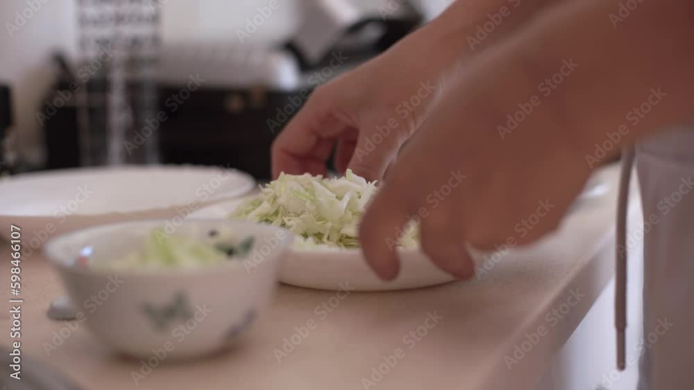 Housewife transfers cut cabbage to smaller bowl for lunch in cozy kitchen. Person prepares snack for delicious dinner on kitchen table Generative AI Housewife transfers cut cabbage to smaller bowl for lunch in cozy kitchen. Person prepares snack for delicious dinner on kitchen table Generative AI