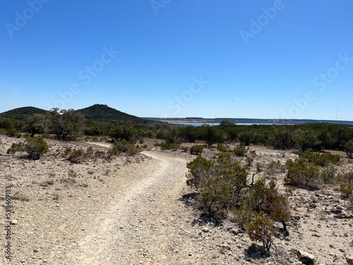 A rocky footpath and hiking trail located at Dana Peak Park hike and bike trail with Stillhouse Hollow Lake in the distant background, located in Harker Heights Texas a part of the Texas Hill Country