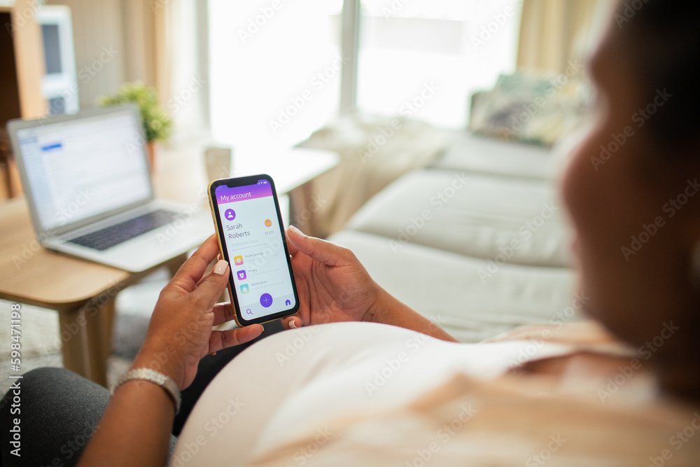 Young pregnant latina woman using a banking app on the couch in the living room Young pregnant latina woman using a banking app on the couch in the living room
