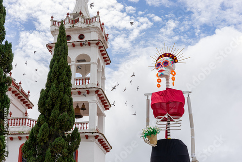 Huge catrina built for the celebration of the day of the dead, white church in the background. photo
