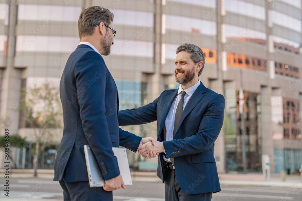 smiling two business men in suit are handshaking in agreement. photo of two business men smiling two business men in suit are handshaking in agreement. photo of two business men