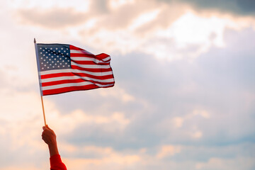Hand Waving the Flag of the United Stated of America. Optimistic person holding American flag celebrating citizenship
