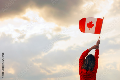 Woman Waving Canadian Flag Looking at the Sky. Optimistic girl holding national flag celebrating citizenship 