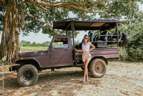 A woman posing with a jeep during a safari in Sri Lanka National Park