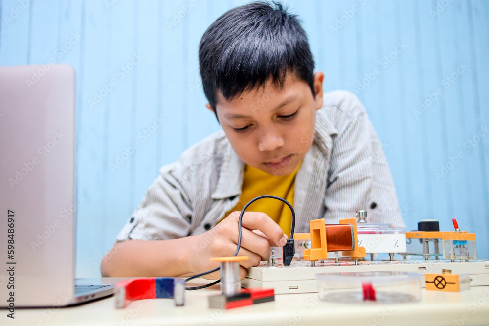 Asian boy working with circuits, wires, computer, motor on his project. Science, Technology, Engineering and Mathematics (STEM) education concept. Asian boy working with circuits, wires, computer, motor on his project. Science, Technology, Engineering and Mathematics (STEM) education concept.
