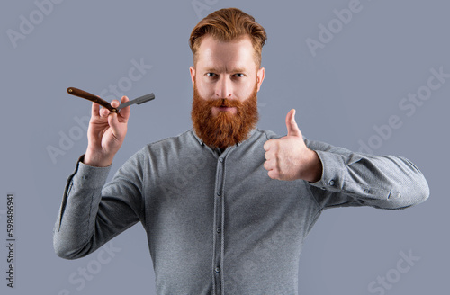 man hold barber blade for shaving showing thumb up. man shaving with barber blade isolated on grey