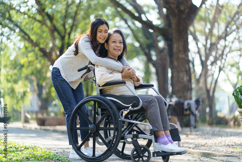 Asian senior woman in wheelchair with happy daughter. Family relationship retired woman sitting on wheelchair in the park age care at retirement home. Asian senior woman in wheelchair with happy daughter. Family relationship retired woman sitting on wheelchair in the park age care at retirement home.