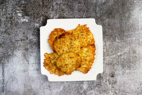 Rustic homemade Zucchini pancakes on a white square  plate on a dark background. Top view, flat lay