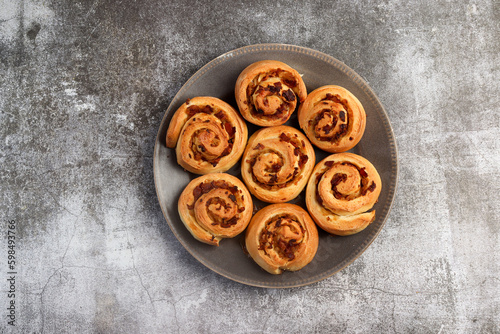 Homemade Savory Bacon Onion Rolls on a round plate on a dark background. Top view, flat lay