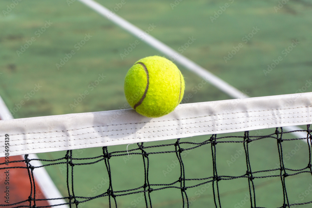 Close up of tennis ball clips the top of the net. tennis ball hit the net and goes to the other side.