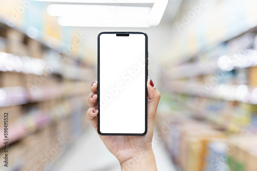Mockup mobile phone with blank white screen. Hand holding smartphone with blurred supermarket background