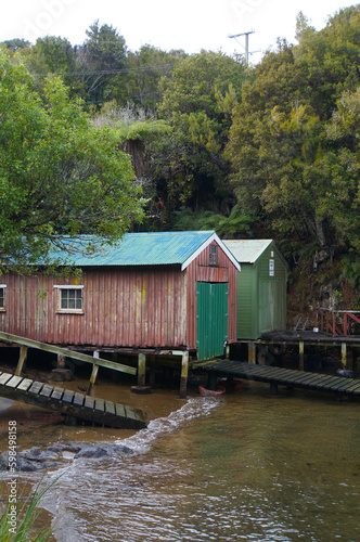 Red and green boathouses and boat ramps in an isolated bay on Stewart Island, New Zealand.