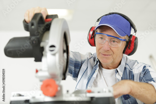 carpenter cutting wooden plank with circular saw wearing safety