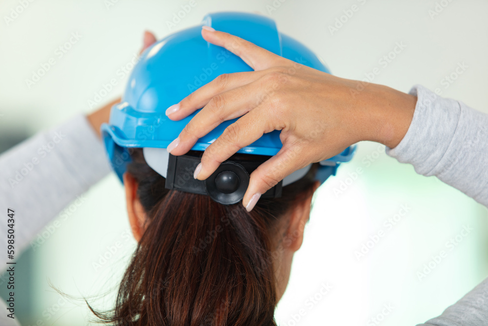 Naklejka premium young female adjusting her safety helmet hardhat