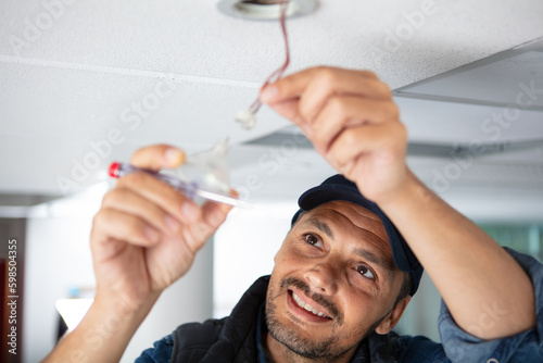 a male electrician fixing light on the ceiling
