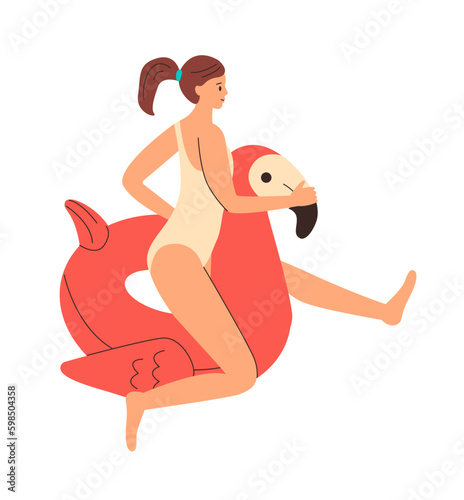 Girl in swimsuit is sitting on an inflatable circle in form of ping flamingo. Colorful rubber inflatable swimming ring.