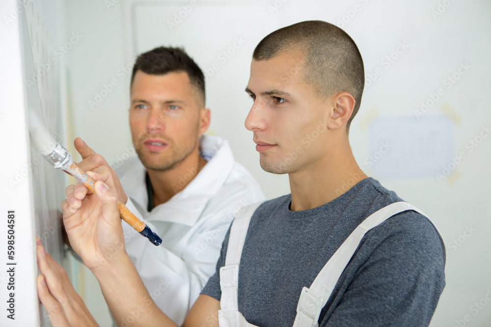 Fototapeta premium apprentices learning how to paint with a thick brush