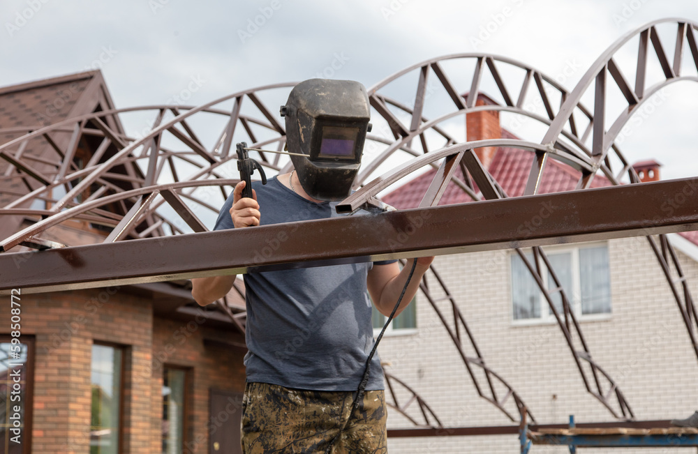 A worker welds metal at a construction site. A worker welds metal at a construction site.