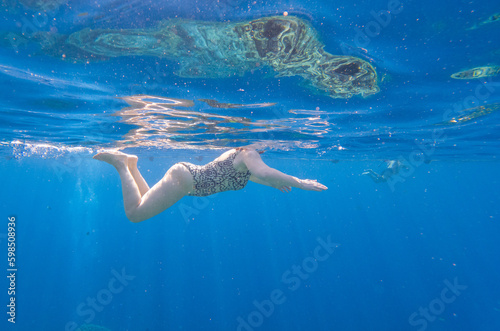 The girl swims underwater in the sea.