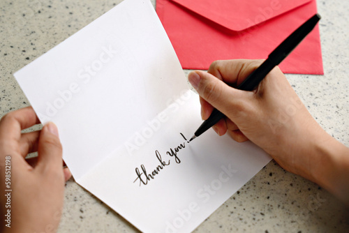 Female hands writing a thank you note with envelope
