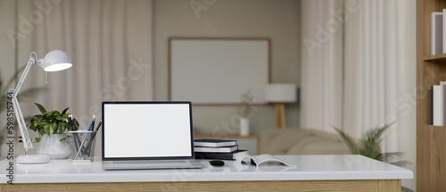 Mock up laptop on the study table with books and stationery, copy space, living room background. © bongkarn