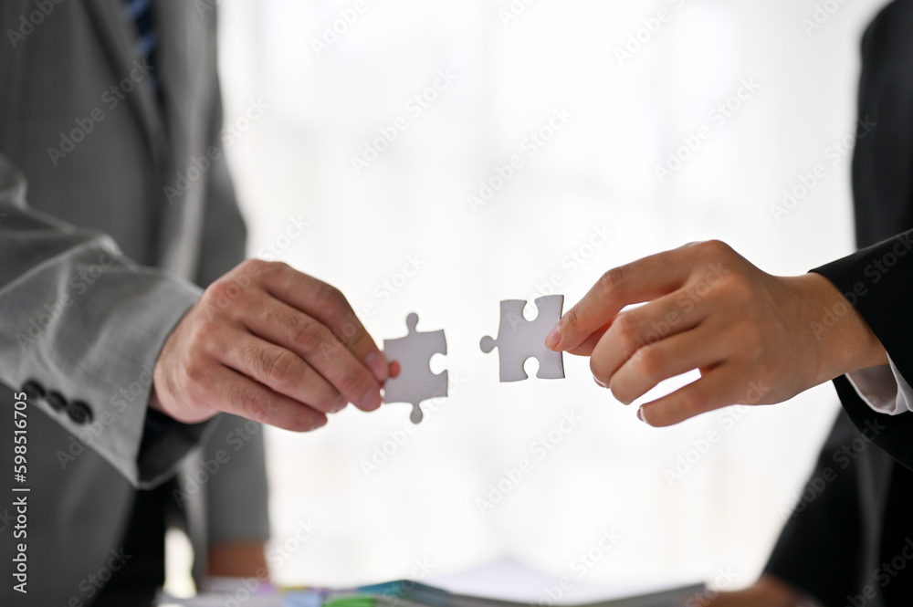 Close-up image of a businessman and a businesswoman holding a jigsaw puzzle