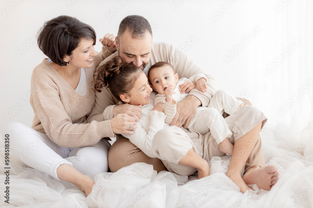 Happy family enjoying together sitting in front of white wall Happy family enjoying together sitting in front of white wall