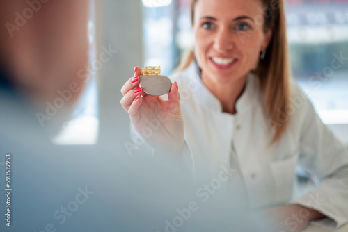 Doctor showing heart pacemaker to patient at clinic photo