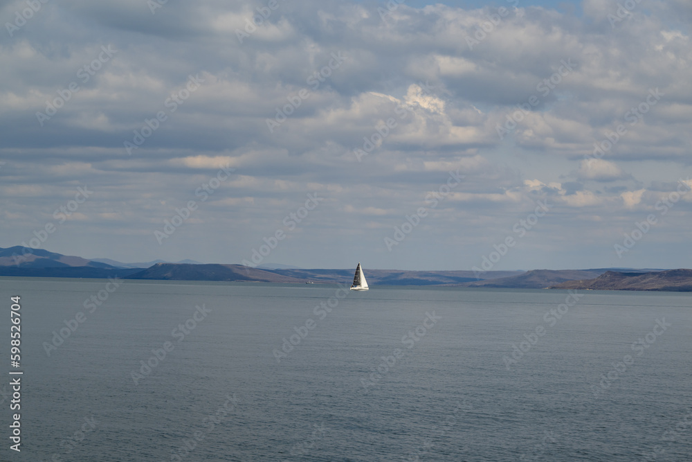 Sailing boat in the sea on a background of blue sky with clouds