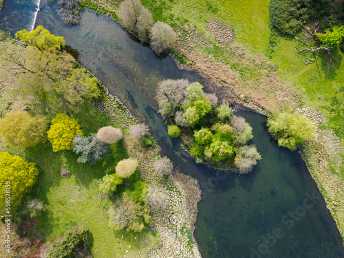 Drone view of a fresh water river seen entry from a large lake. A small natural river Island is seen. In the area of rare white deer which can be seen grazing below.