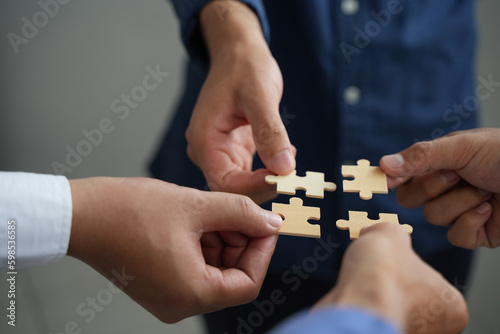 The concept of teamwork and partnership Hands joining puzzle pieces in office Businessmen put together a jigsaw puzzle - volunteer charity team business uniy.