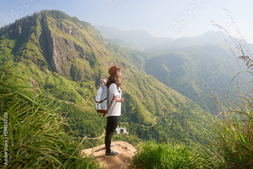 Woman traveler enjoying early morning beautiful nature on background of mountain peak "Adam's Peak", Sri Lanka.