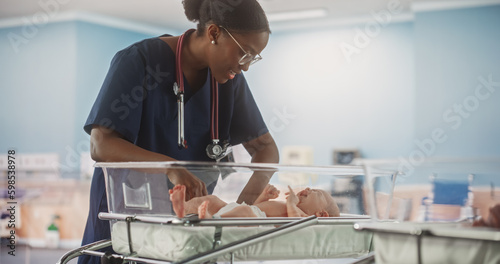 Professional African Nurse Soothing an Adorable Small Caucasian Newborn Child in Nursery Clinic. Medical Health Care, Maternity Hospital and Parenthood Concept