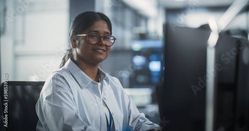 Portrait of Beautiful Smiling IT Specialist Posing for Camera in Data Science Laboratory. Young Indian Female Looking at Camera. Succesful Woman Working in Big Server Farm Cloud Computing Company
