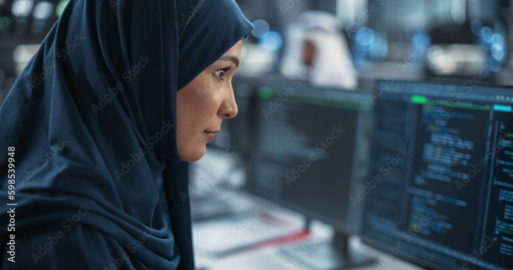 Portrait of a Smart Focused Middle Eastern Engineer Working on Computer in a Technological Corporate Office. Young Arab Woman in Hijab Developing Software for an Innovative Internet Service Provider Portrait of a Smart Focused Middle Eastern Engineer Working on Computer in a Technological Corporate Office. Young Arab Woman in Hijab Developing Software for an Innovative Internet Service Provider