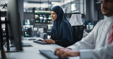 Beautiful Middle Eastern Computer Scientist Wearing a Hijab, Working on PC in a Technological Corporate Office. Young Muslim Woman Writing Software Code for an Innovative Online Service Project