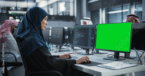 Arab Female Software Developer Working on Desktop Computer with Green Screen Mock Up Display. Young Middle Eastern Specialist Testing Programming Code for an Innovative Big Data Blockchain Project