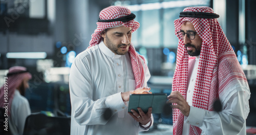 Foto Two Young Muslim Software Engineers Use Tablet Computer to Discuss a Technological Project in a Modern Industrial Office