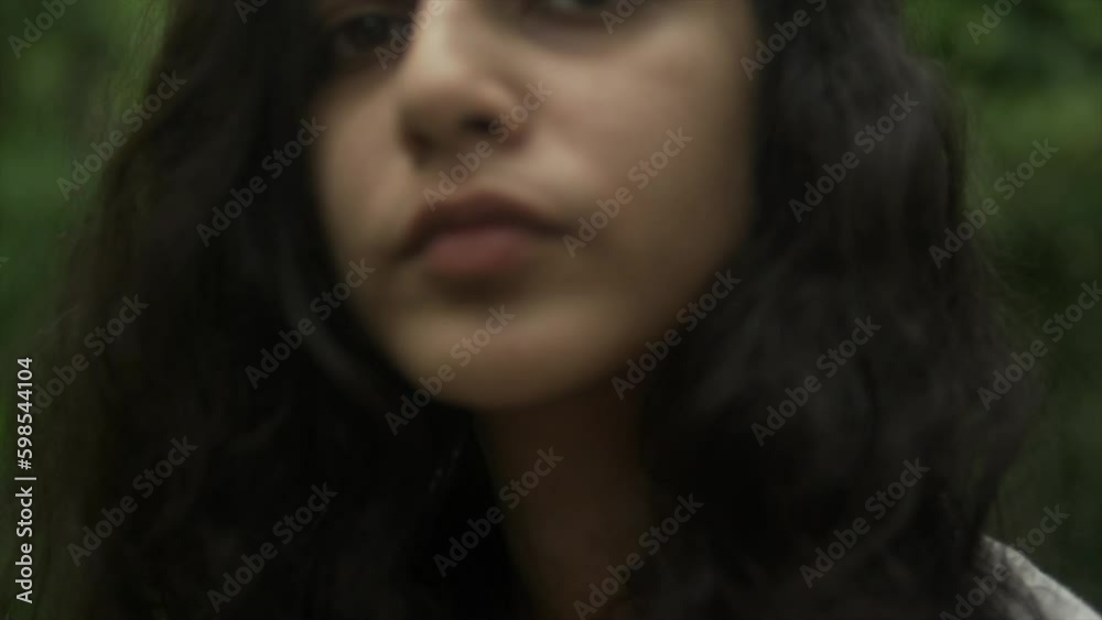 close-up view of a solitary and pensive woman with black hair, situated in the heart of a forest surrounded by nature close-up view of a solitary and pensive woman with black hair, situated in the heart of a forest surrounded by nature