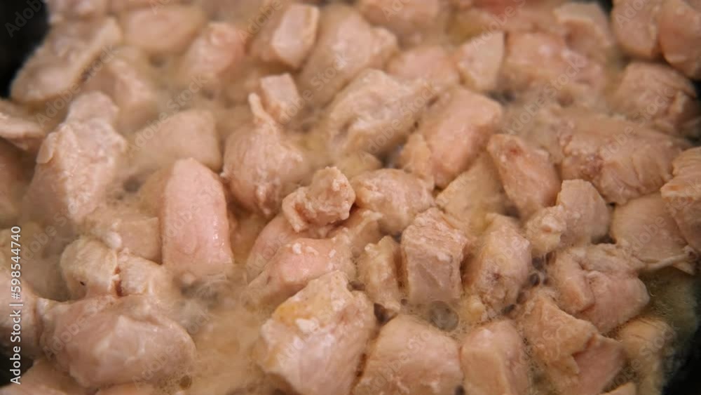 Process of frying chopped chicken breast pieces. Close-up. Roasting chicken fillet in black frying pan. Stewed poultry Recipe. Eco trend. Fresh raw white meat cooked in a steamer. Diet food. Overhead. Process of frying chopped chicken breast pieces. Close-up. Roasting chicken fillet in black frying pan. Stewed poultry Recipe. Eco trend. Fresh raw white meat cooked in a steamer. Diet food. Overhead.