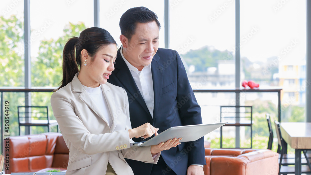 Asian professional successful female businesswoman secretary employee showing information strategy data via laptop notebook computer to male businessman manager in formal business suit in living room Asian professional successful female businesswoman secretary employee showing information strategy data via laptop notebook computer to male businessman manager in formal business suit in living room