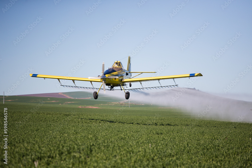 Close up image of crop duster airplane spraying grain crops on a field on a farm - obrazy, fototapety, plakaty 