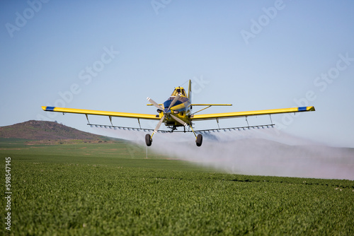 Close up image of crop duster airplane spraying grain crops on a field on a farm