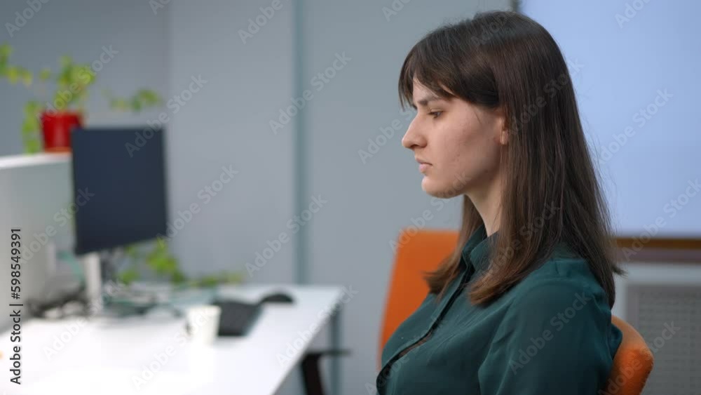 Side view tired woman rubbing temples in slow motion sitting in office. Portrait of exhausted overworked Caucasian female employee indoors Side view tired woman rubbing temples in slow motion sitting in office. Portrait of exhausted overworked Caucasian female employee indoors