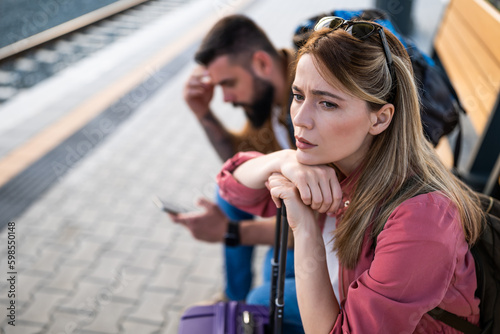 Foto Anxious and tired couple sitting at railway station and waiting for arrival of their train
