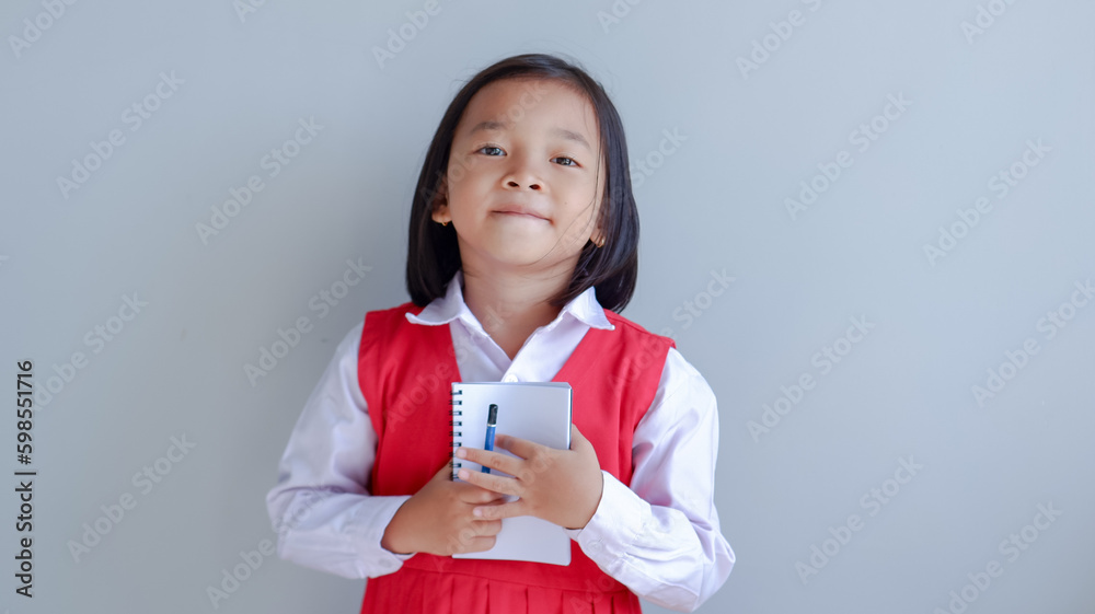 young asian girl wearing school uniform and holding small note book young asian girl wearing school uniform and holding small note book