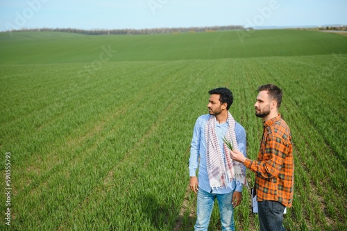 Two indian farmers standing at agriculture field.