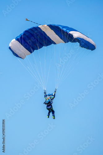 Skydiving. Flying parachutists against the background of the blue sky and mountains. Extreme sport and entertainment.