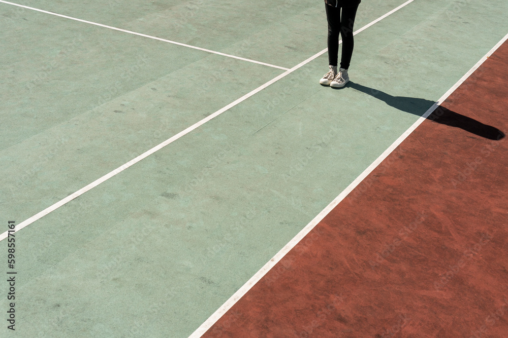 Teenage girl standing on rubberized tennis court