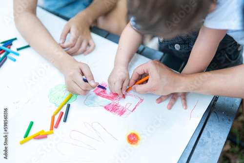 A family draws on paper lying on their free time on the table.